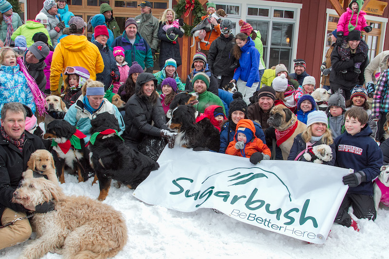 Group of people smiling in front of a Sugarbush banner